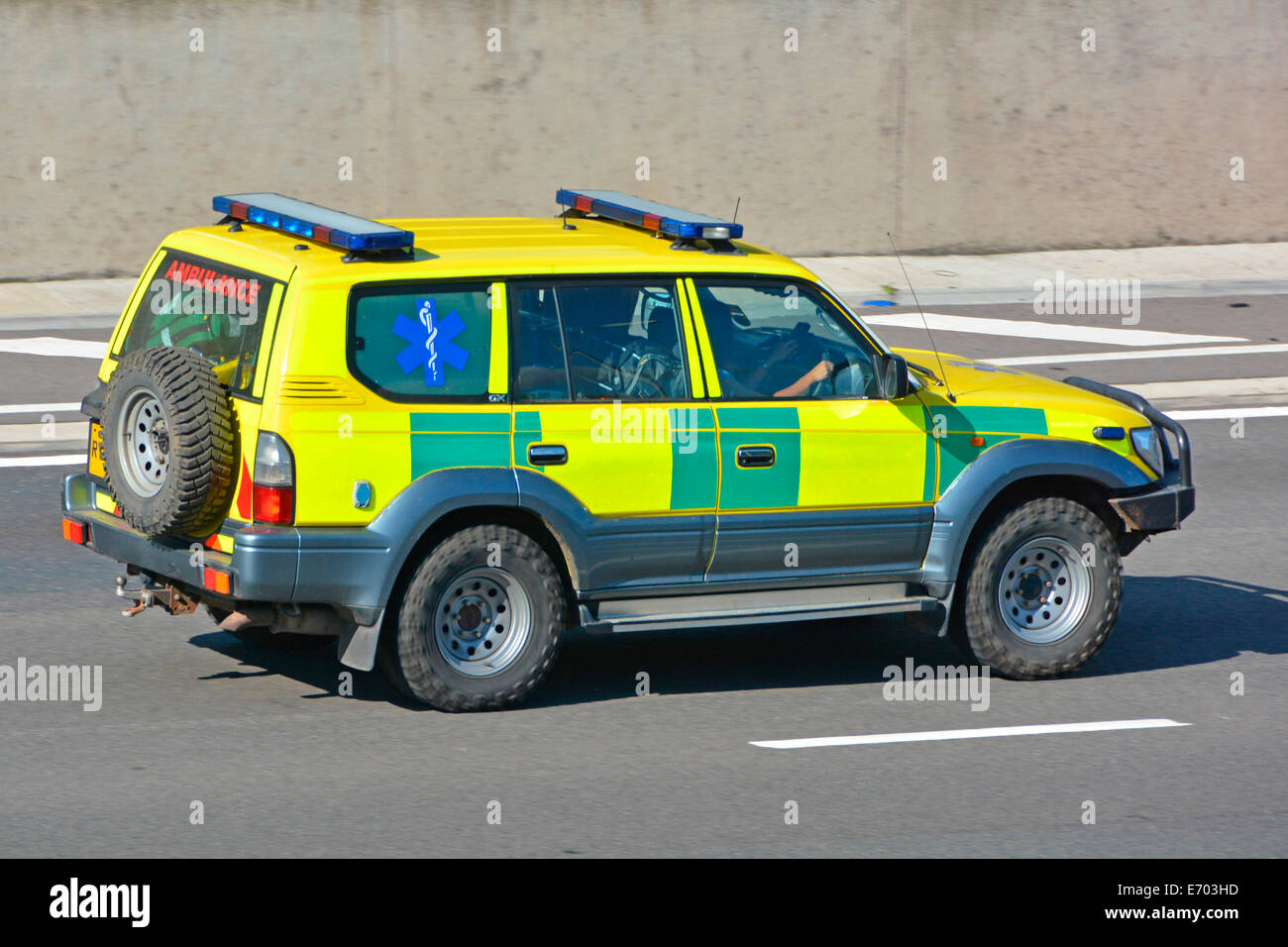 Battenburg Markierungen auf der Seite des Krankenwagens angenommen, privat zu sein Betrieb mit Reifen mit starkem Profil und Notlicht beim Fahren Entlang der britischen Autobahn Stockfoto