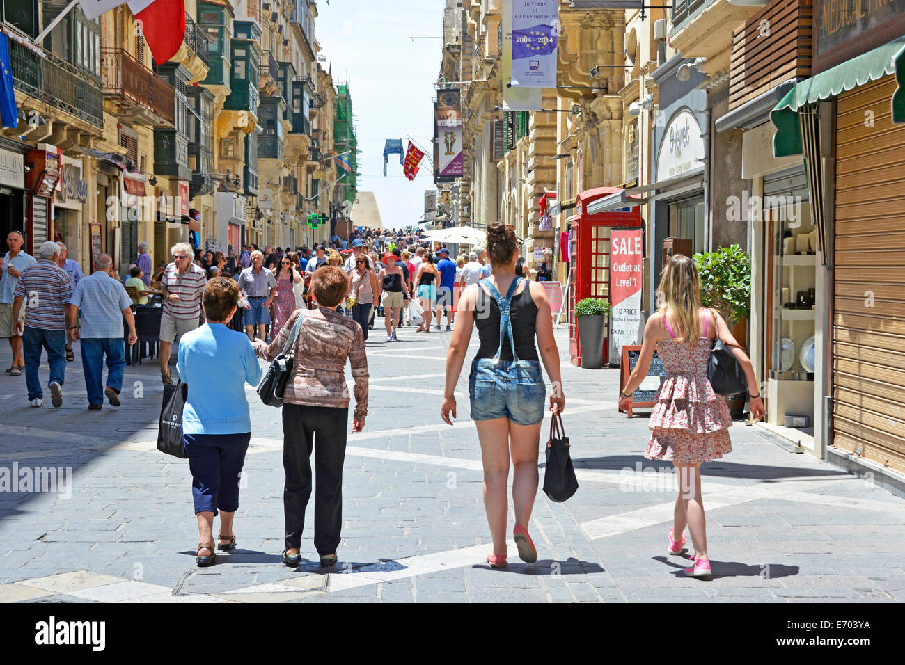 Rückansicht vier nächstgelegene Frauen Käufer und oder Touristen in verschiedenen Mode-Kleidung Aussagen sonnig einkaufen Fußgängerzone Republic Street Valletta Malta Stockfoto