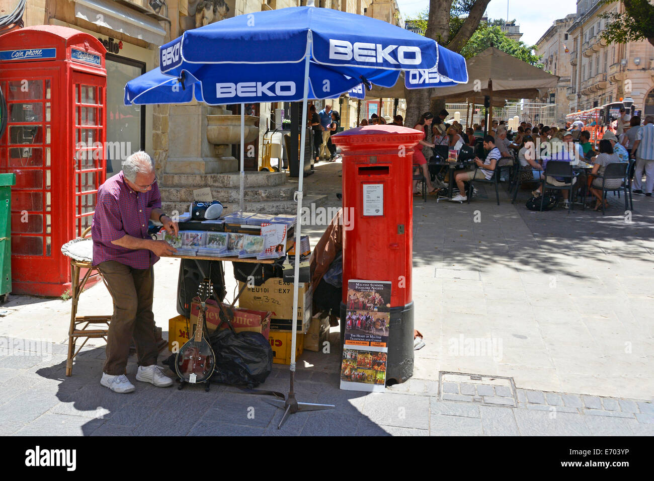 Valletta-Stadtzentrum Mann Einrichten von einem kleinen Stall CDs unter Sonnenschirmen neben roten UK Briefkasten an einem heißen Sommertag Stockfoto