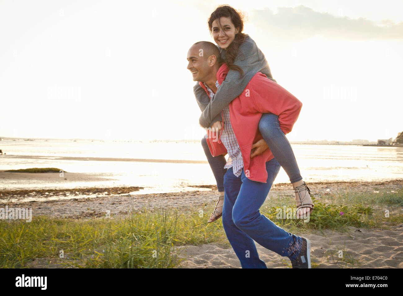 Mann, die Frau am Strand Huckepack Fahrt geben Stockfoto