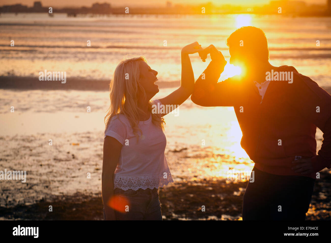 Paar bilden Herzform mit Armen am Strand bei Sonnenuntergang Stockfoto