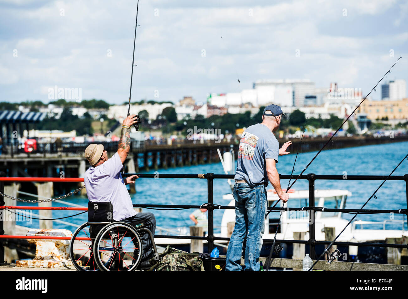 Behinderte Menschen in einem Rollstuhl Angeln von einem Pier. Stockfoto