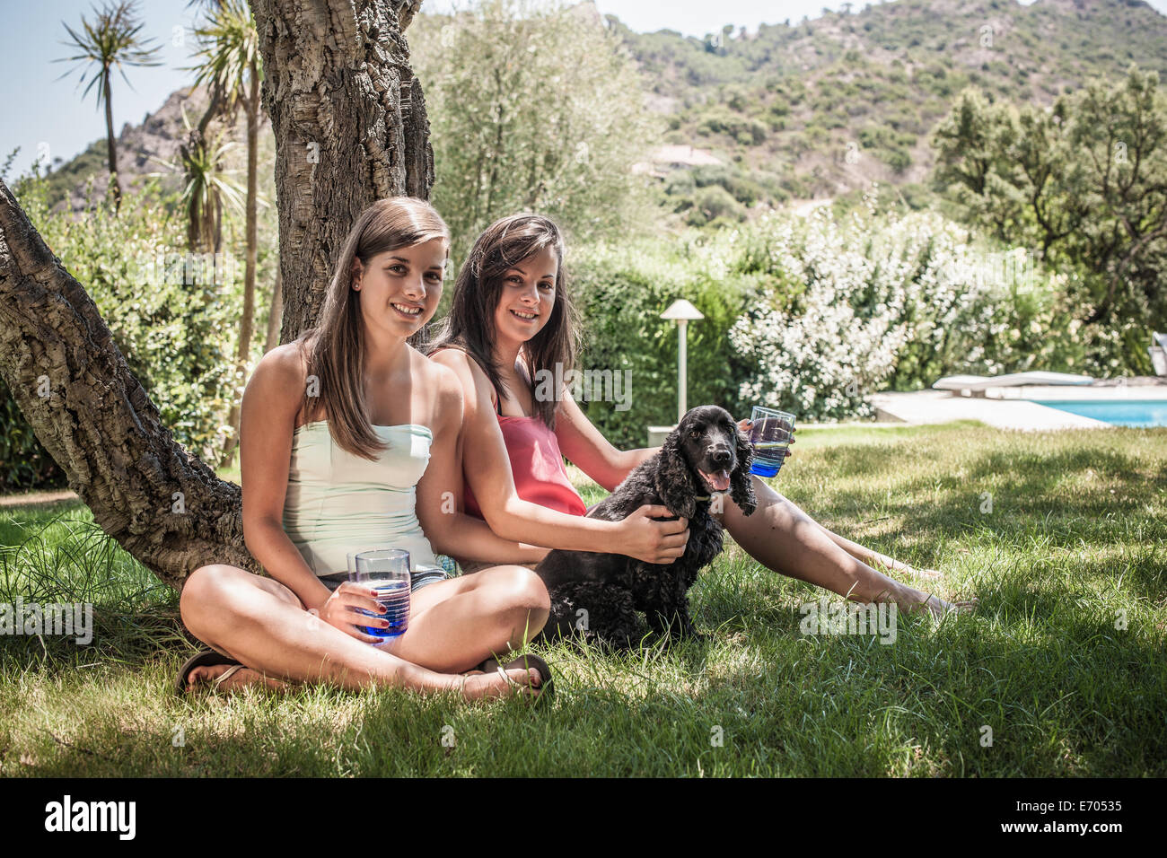 Porträt von zwei Freundinnen mit Hund im Urlaub Hausgarten, Capoterra, Sardinien, Italien Stockfoto