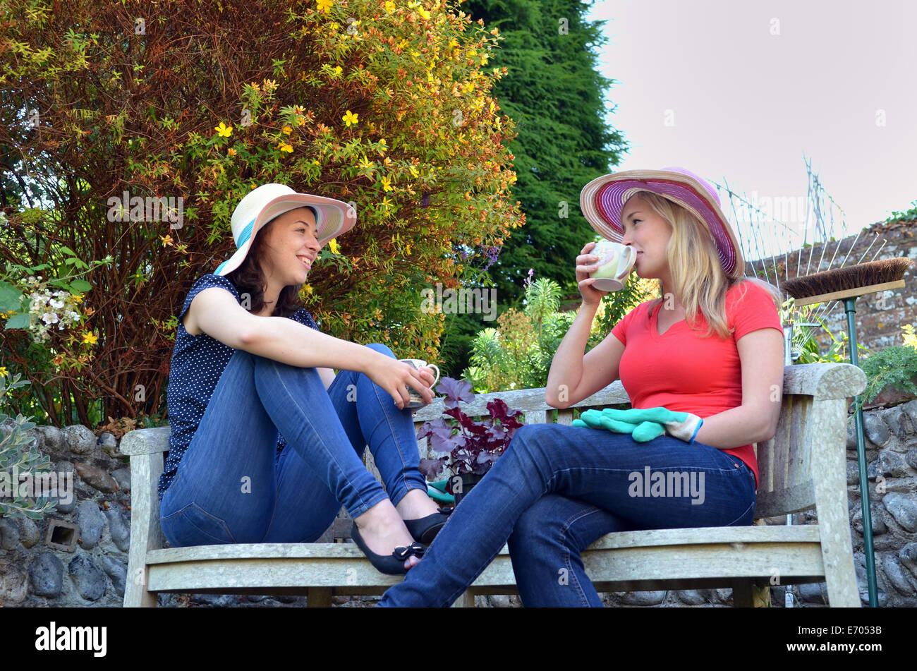 Porträt der jungen Frauen sitzen auf Bank Tee trinken Stockfoto
