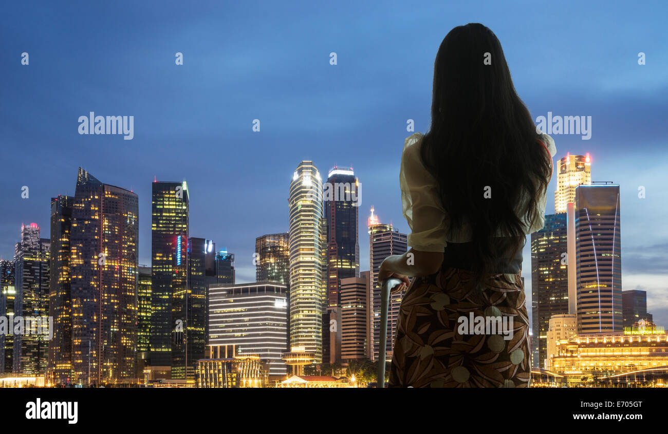 Junge Frau mit Blick auf die Skyline der Stadt Koffer Stockfoto