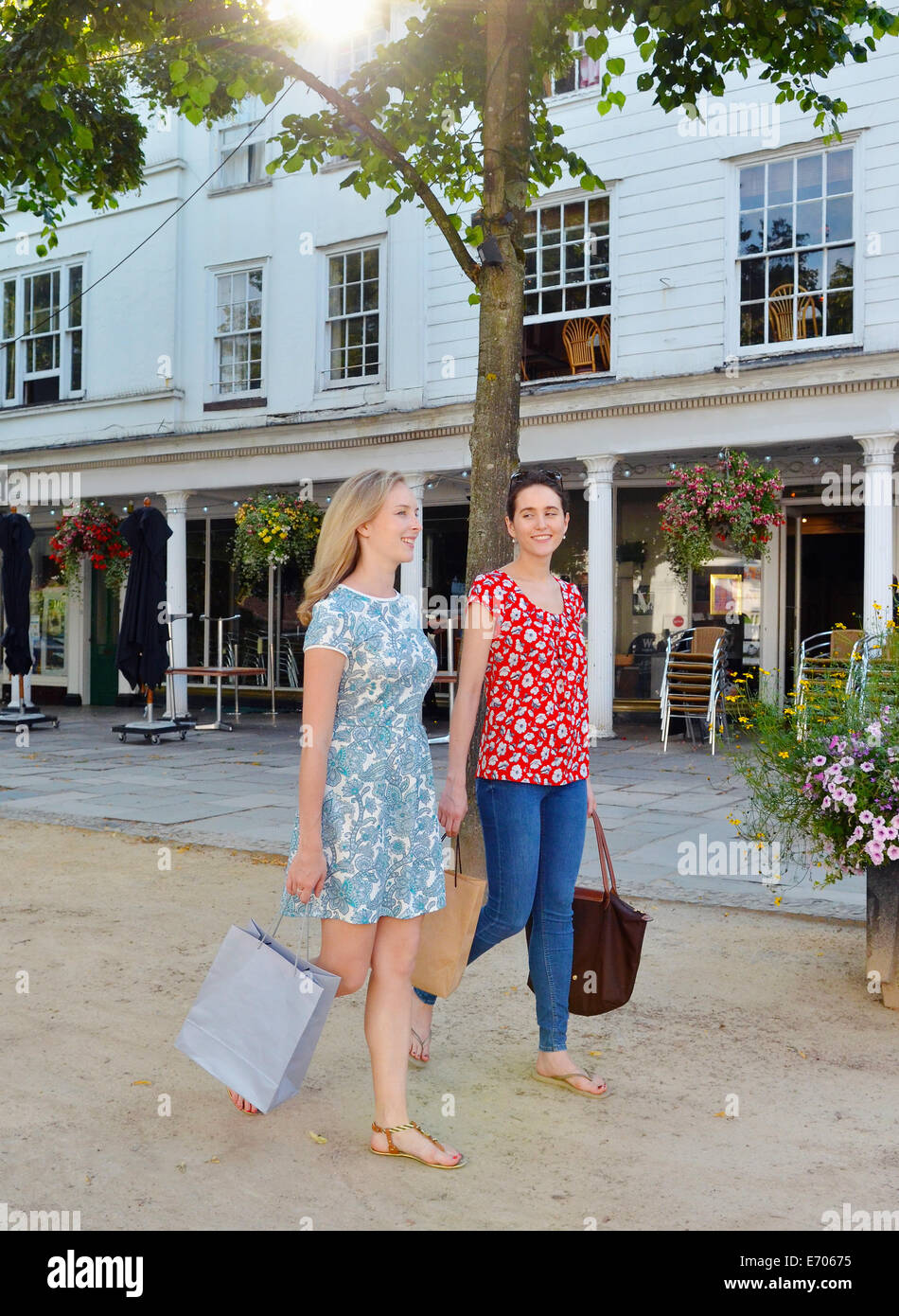 Zwei junge Frauen, die ein Spaziergang entlang der Straße Einkaufstaschen tragen Stockfoto