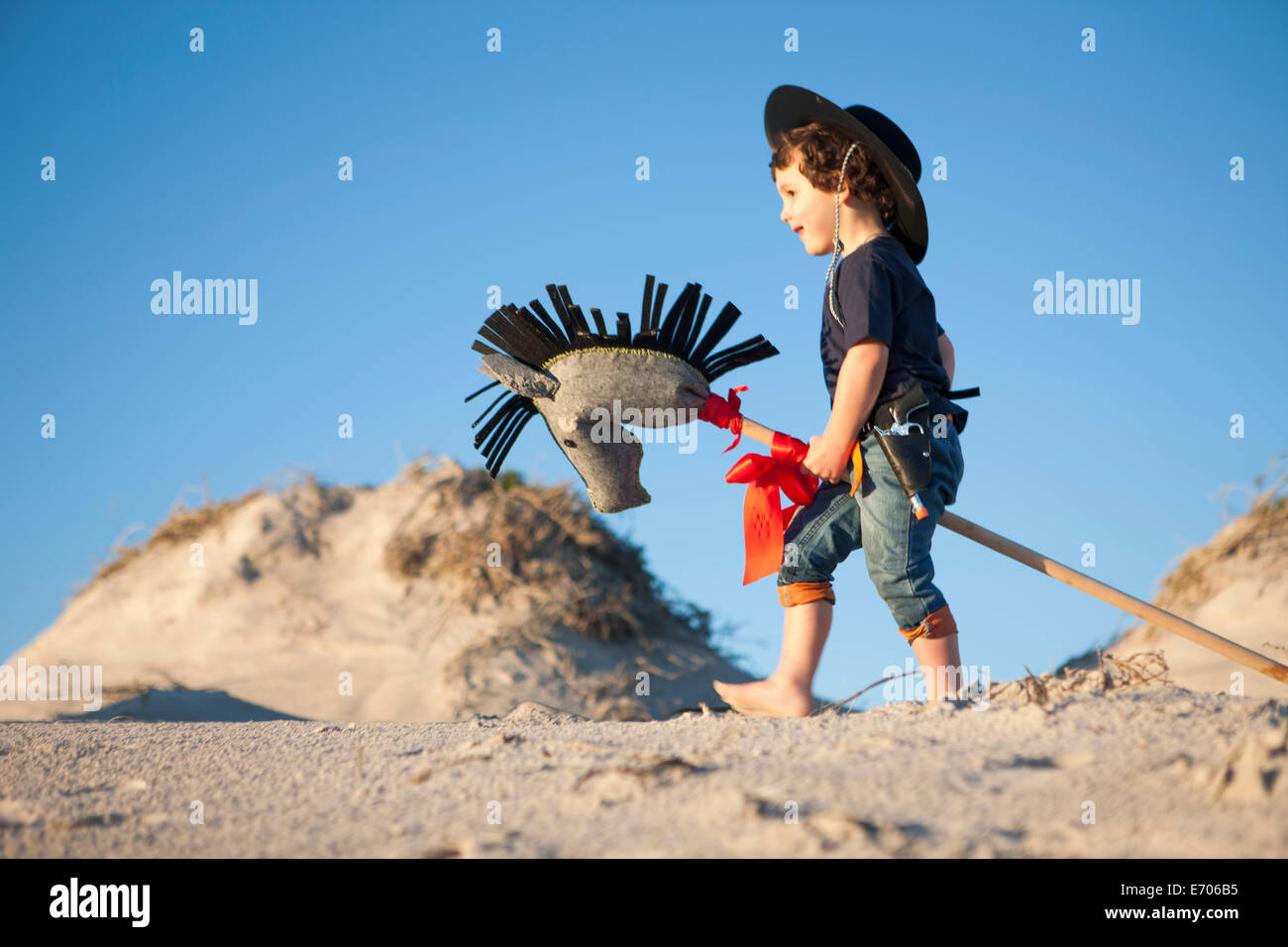 Junge verkleidet als Cowboy mit Steckenpferd in Sanddünen Stockfoto