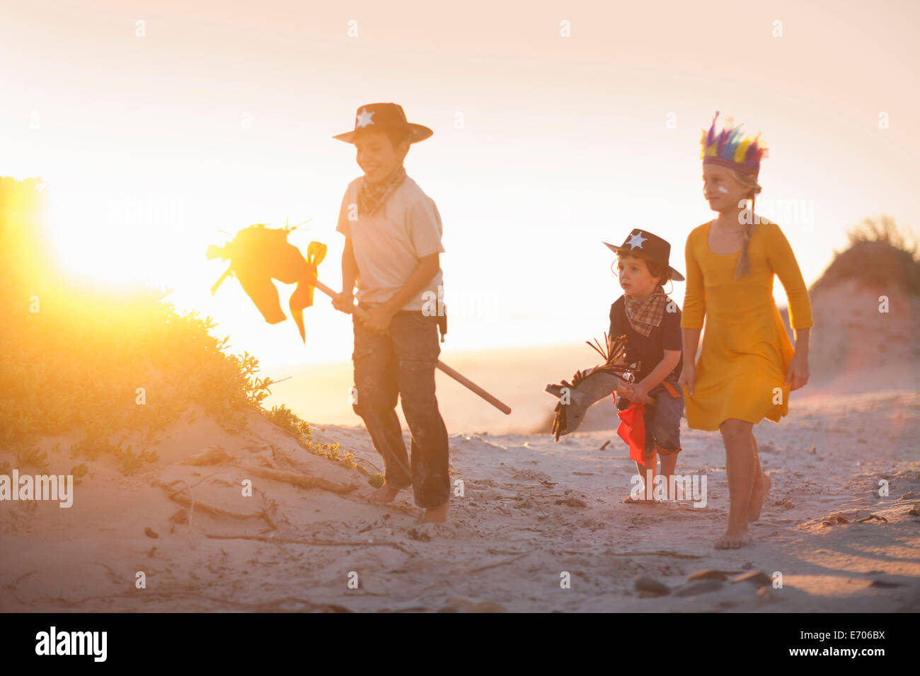Drei Kinder, verkleidet als Indianer und Cowboys in Sanddünen Stockfoto