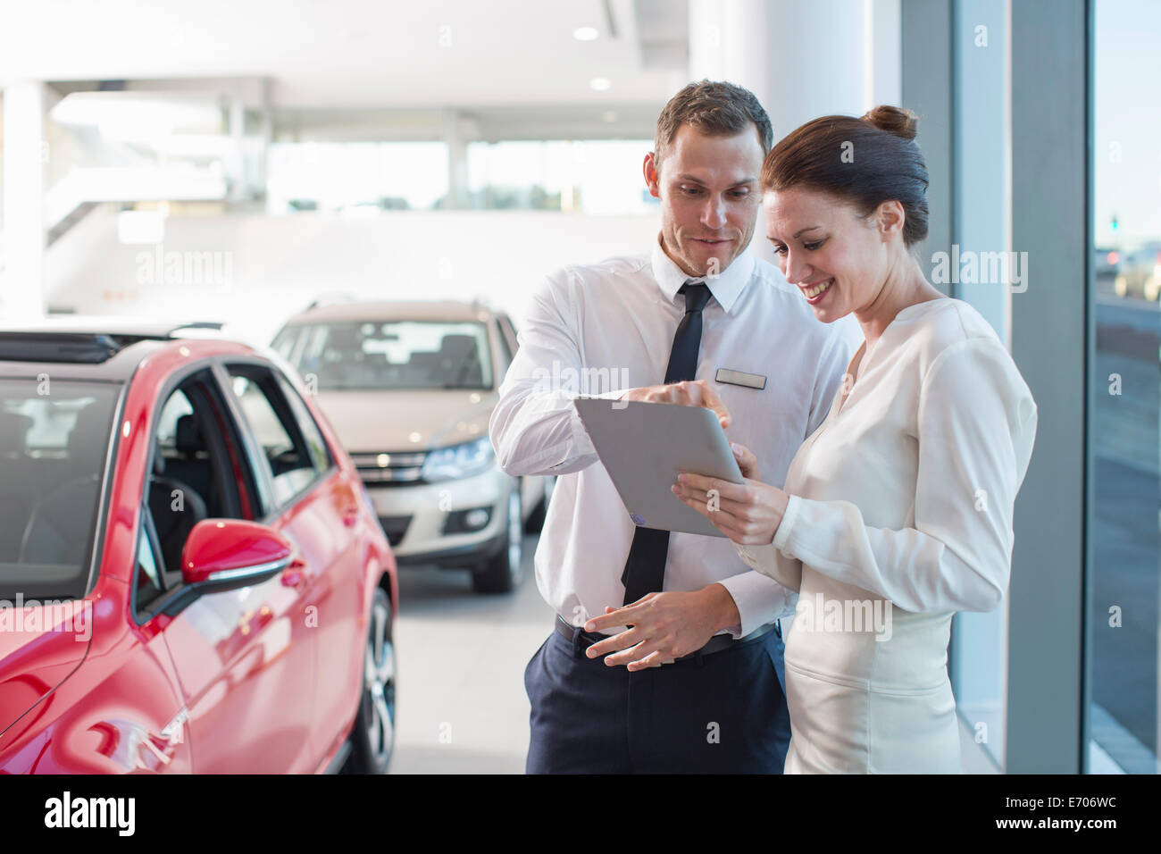 Verkäufer und weibliche Kunden mit digital-Tablette im Autohaus Stockfoto