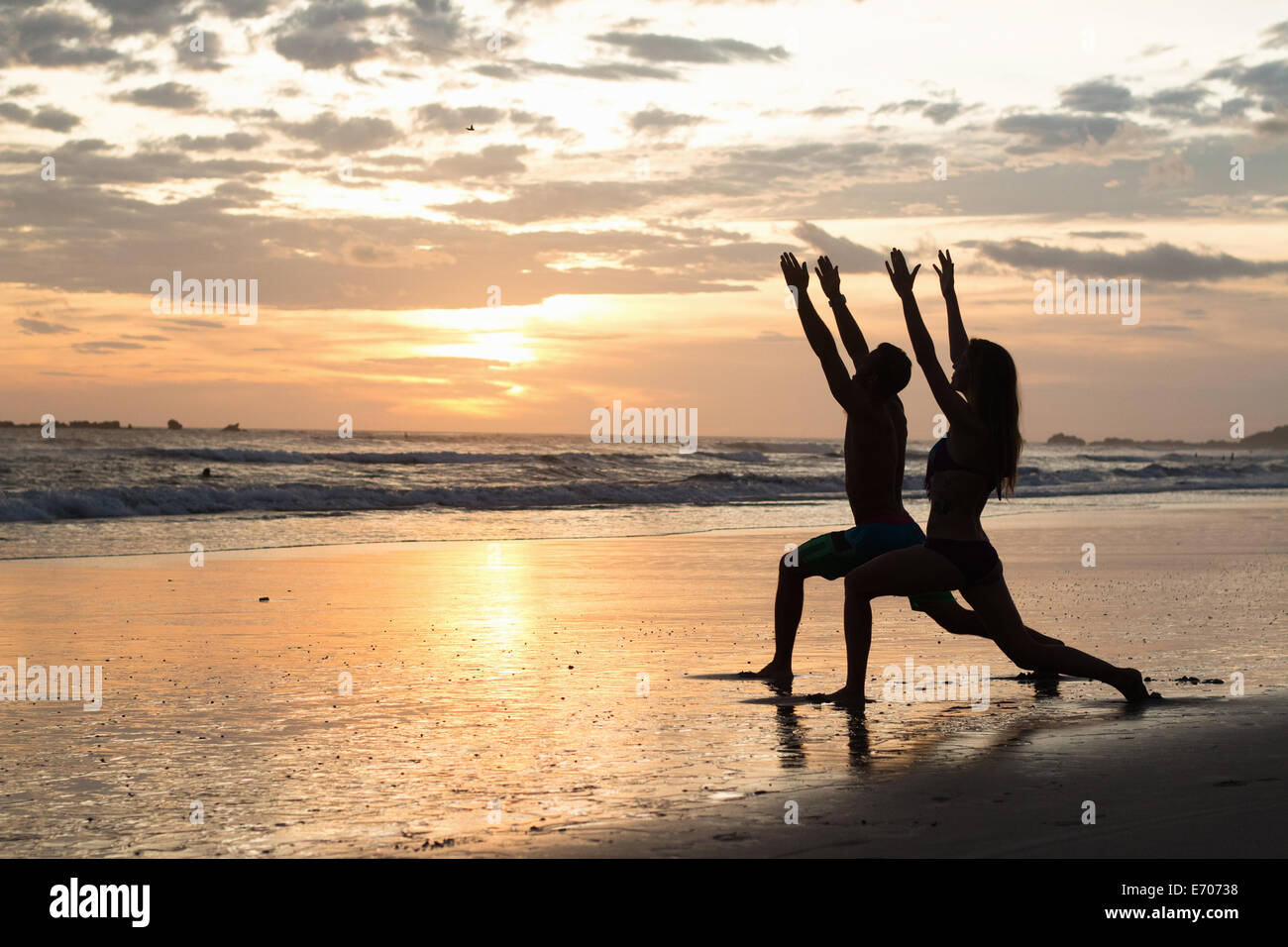 Paar tun stretching-Übungen am Strand bei Sonnenuntergang, Nosara, Guanacaste, Costa Rica Stockfoto