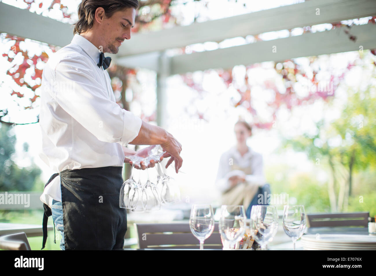 Kellner, die Weingläser auf Tisch im Restaurant Patio vorbereiten Stockfoto