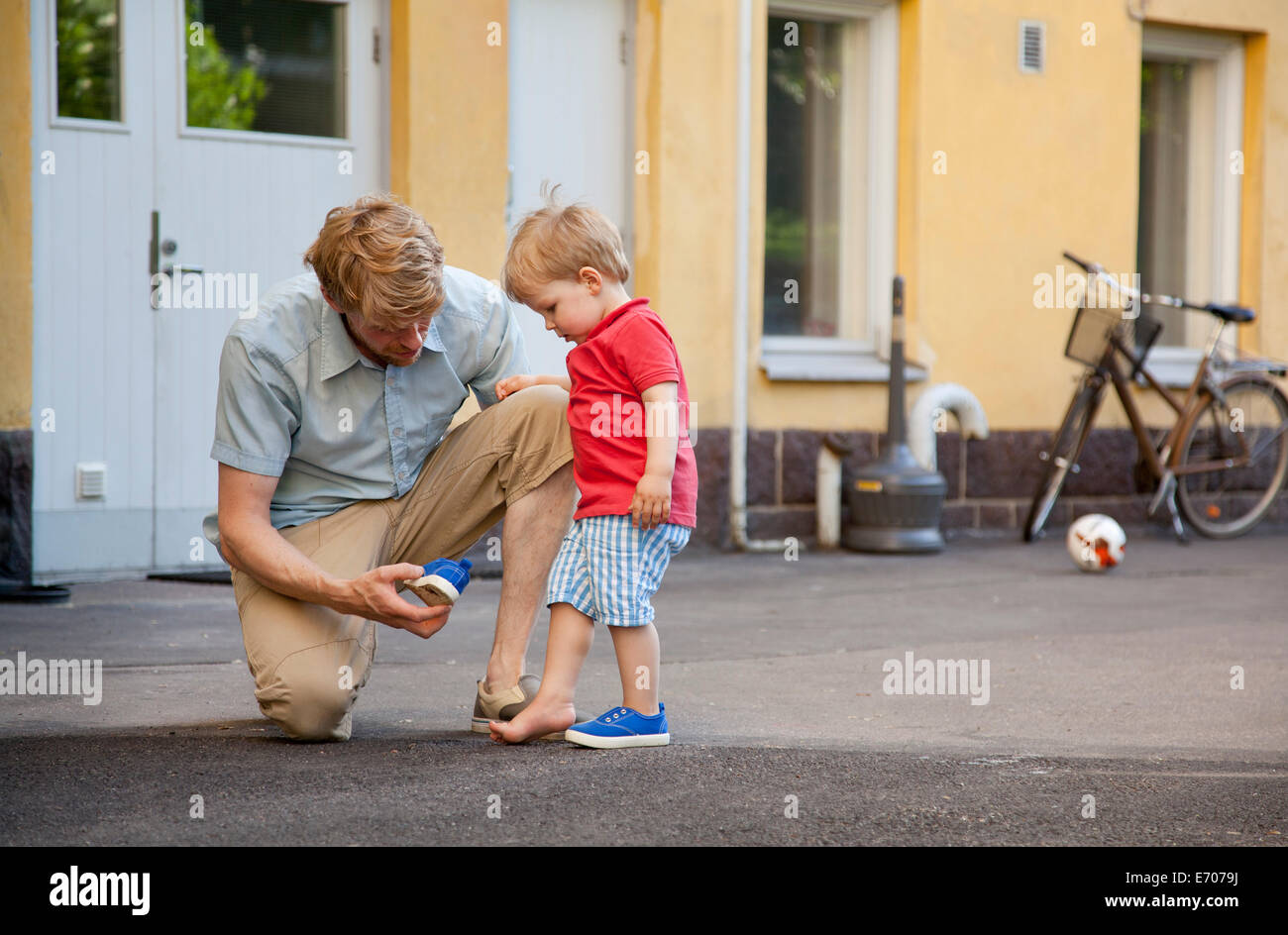 Vater den kleinen Sohn eine Hand auf Trainer im Garten setzen Stockfoto