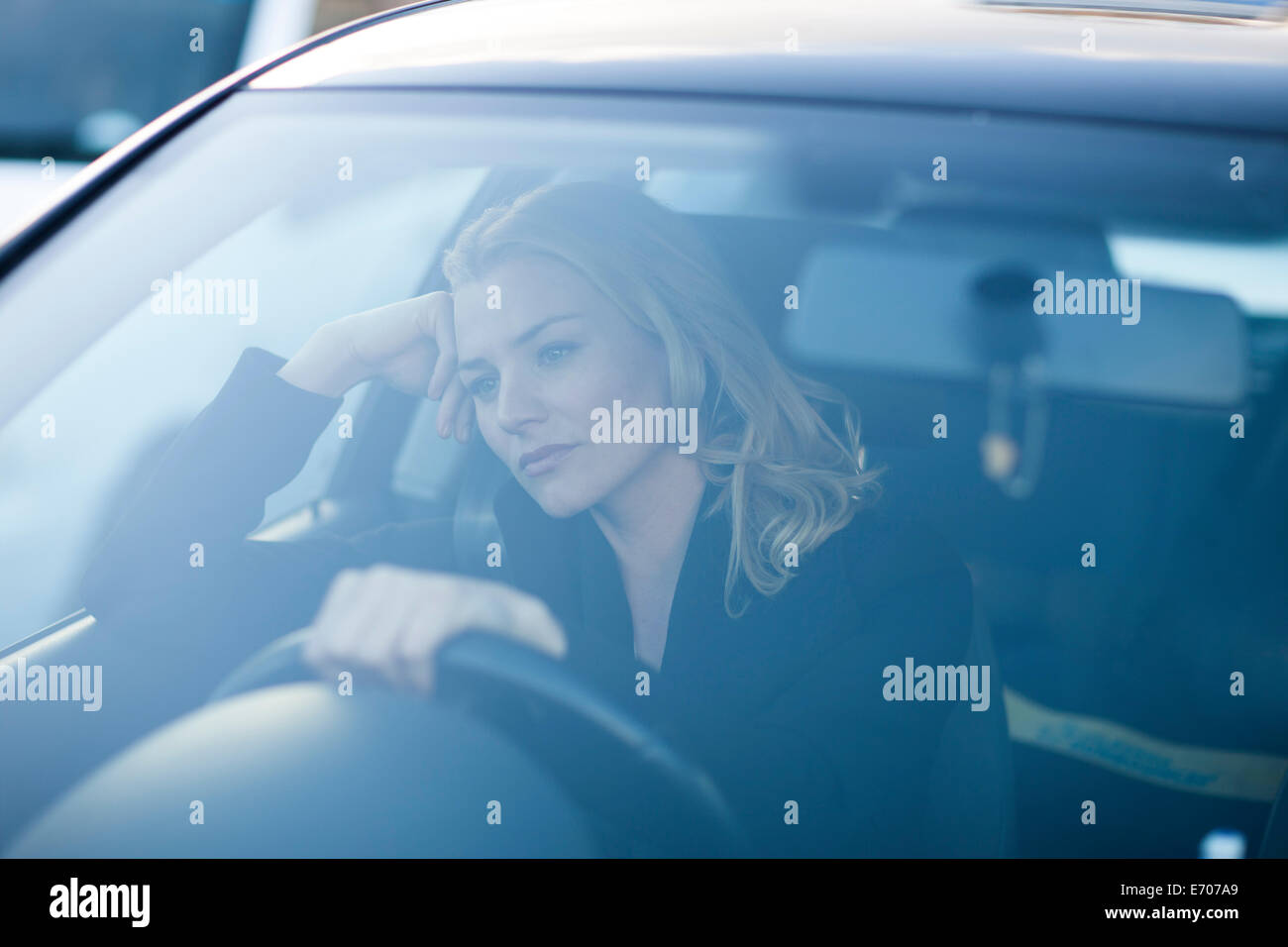 Gelangweilte Geschäftsfrau starrte während der Fahrt in die Stadt-Stau Stockfoto