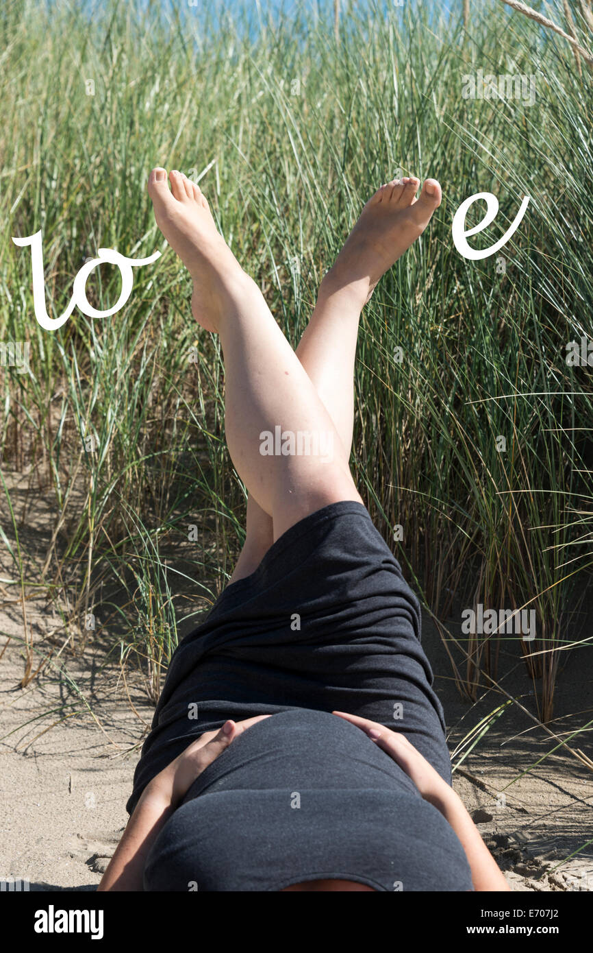 Schwangere Frau mit Liebesbriefe auf dem Bauch im sand Stockfoto