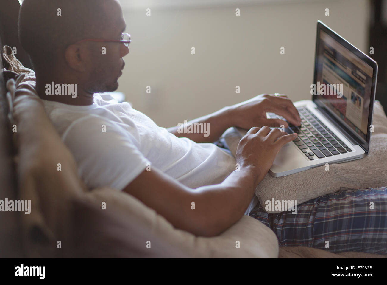 Mitte Erwachsener liegend Mann, auf Bett, mit laptop Stockfoto