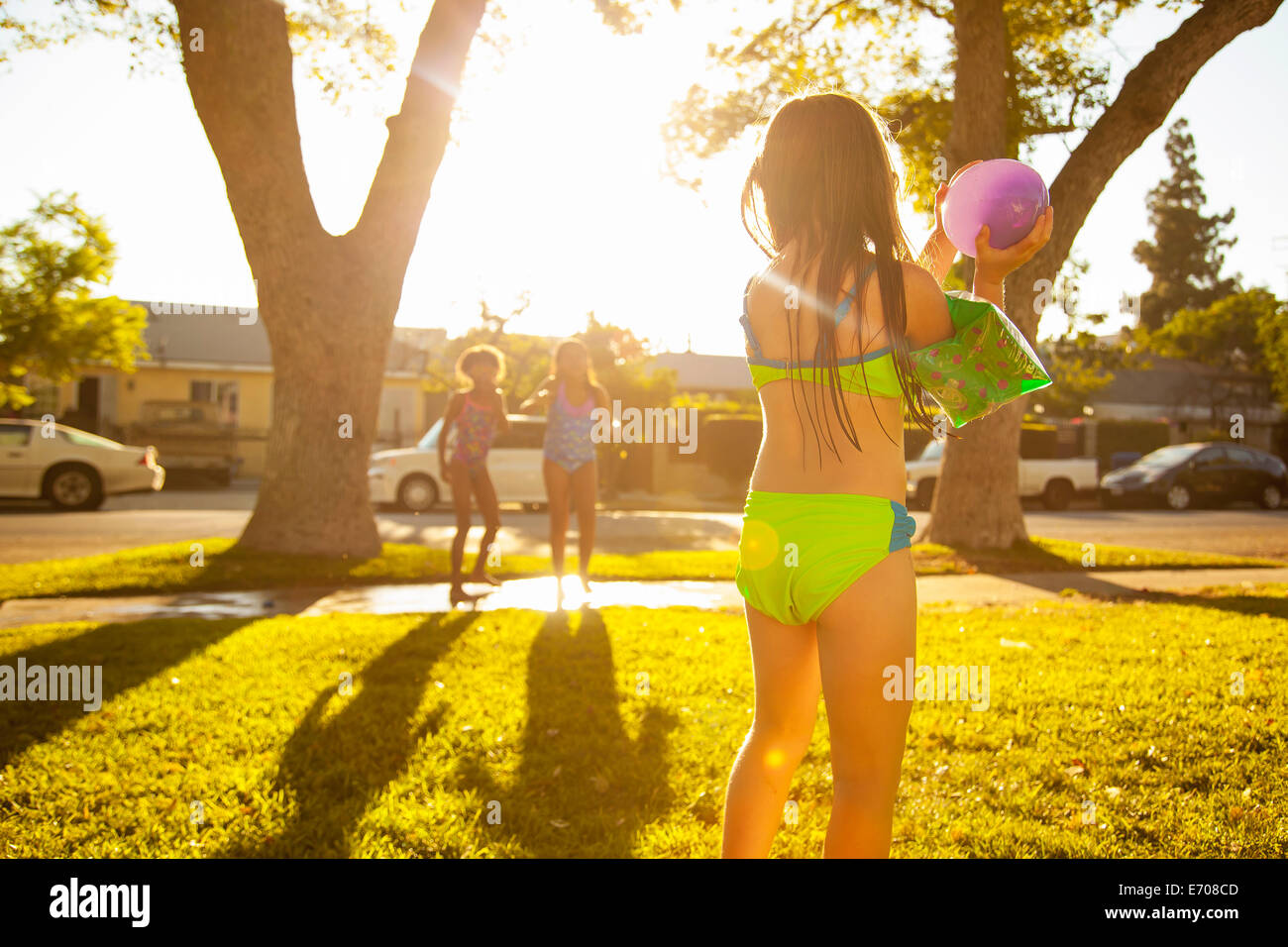 Mädchen jagen Freunde mit Wasser gefüllten Ballons im Garten Stockfoto