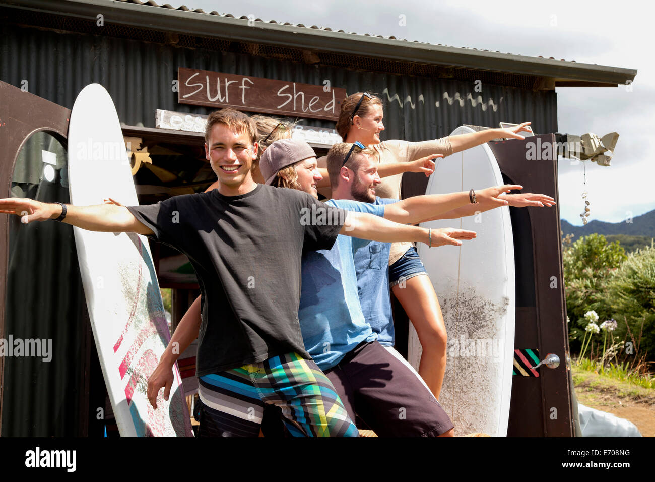 Gruppenbild von fünf junge Erwachsene Surfer Freunden posiert mit ausgestreckten Armen Stockfoto