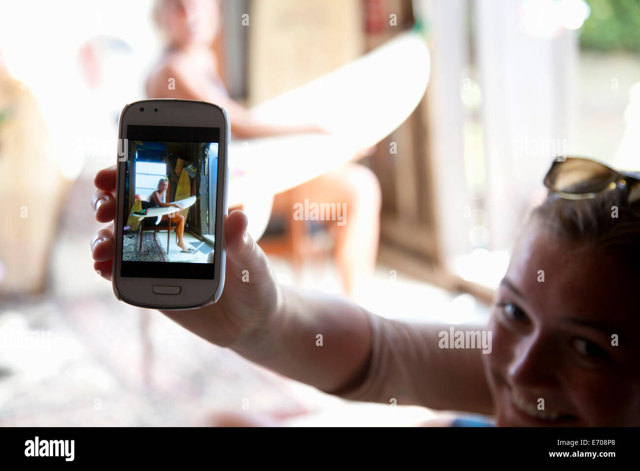 Junge Frau hält Smartphone mit Foto von ihrer besten Freundin Stockfoto