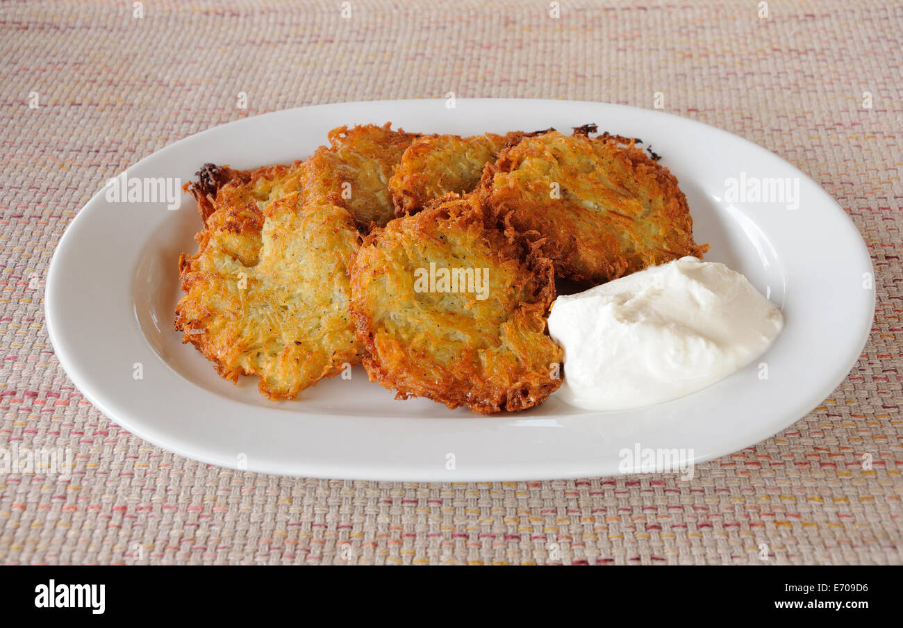 Kartoffelpuffer mit saurer Sahne auf weißen Teller Stockfoto