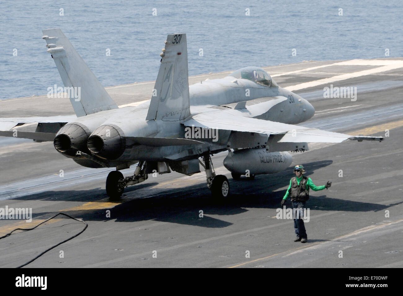 Ein US-Marine Seemann direkt ein Kampfflugzeug F/A - 18C Hornet in Position für Take off aus das Flugdeck des Flugzeugträgers USS George H.W. Bush 30. August 2014 im Persischen Golf. Die Piloten fliegen gezielte Luftangriffe gegen Extremisten bekannt als der islamische Staat im Irak und in der Levante. Stockfoto