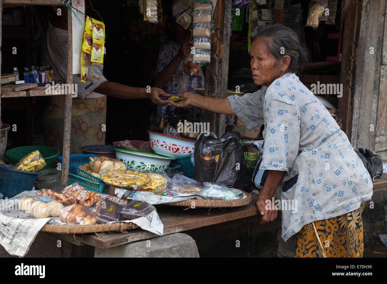 Borobudur, Java, Indonesien.  Frau, die einen Kauf auf einen Dorfladen. Stockfoto
