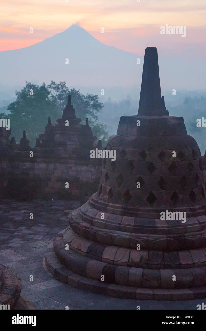 Borobudur, Java, Indonesien.  Stupa und Mount Merapi bei Sonnenaufgang im Morgennebel. Stockfoto