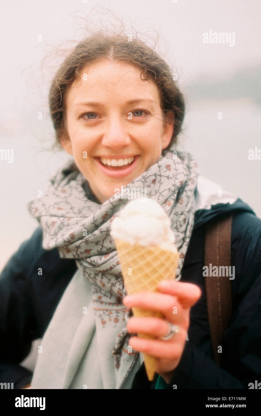 Eine Frau hält sich ein Eis in einem Kegel und lachen. Stockfoto