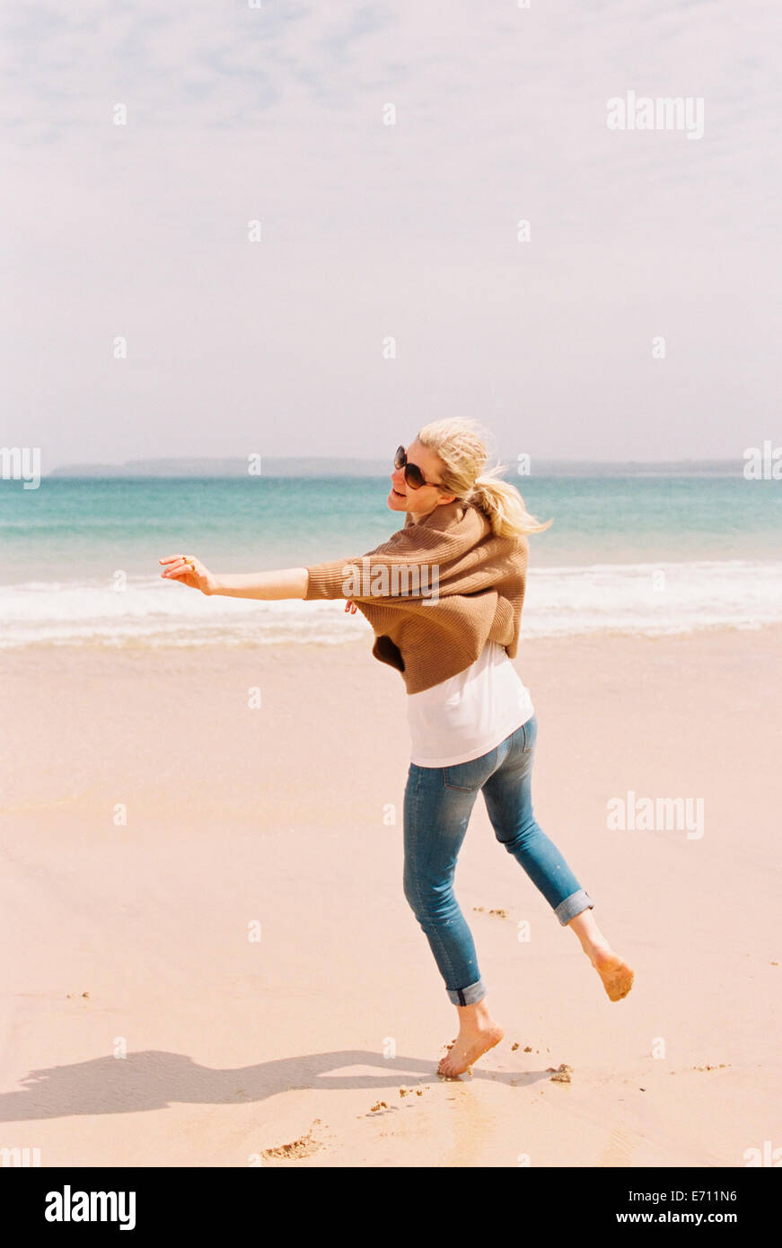 Eine Frau tanzt barfuß im Sand selbst durch Bewegungen zum Ausdruck zu bringen. Stockfoto