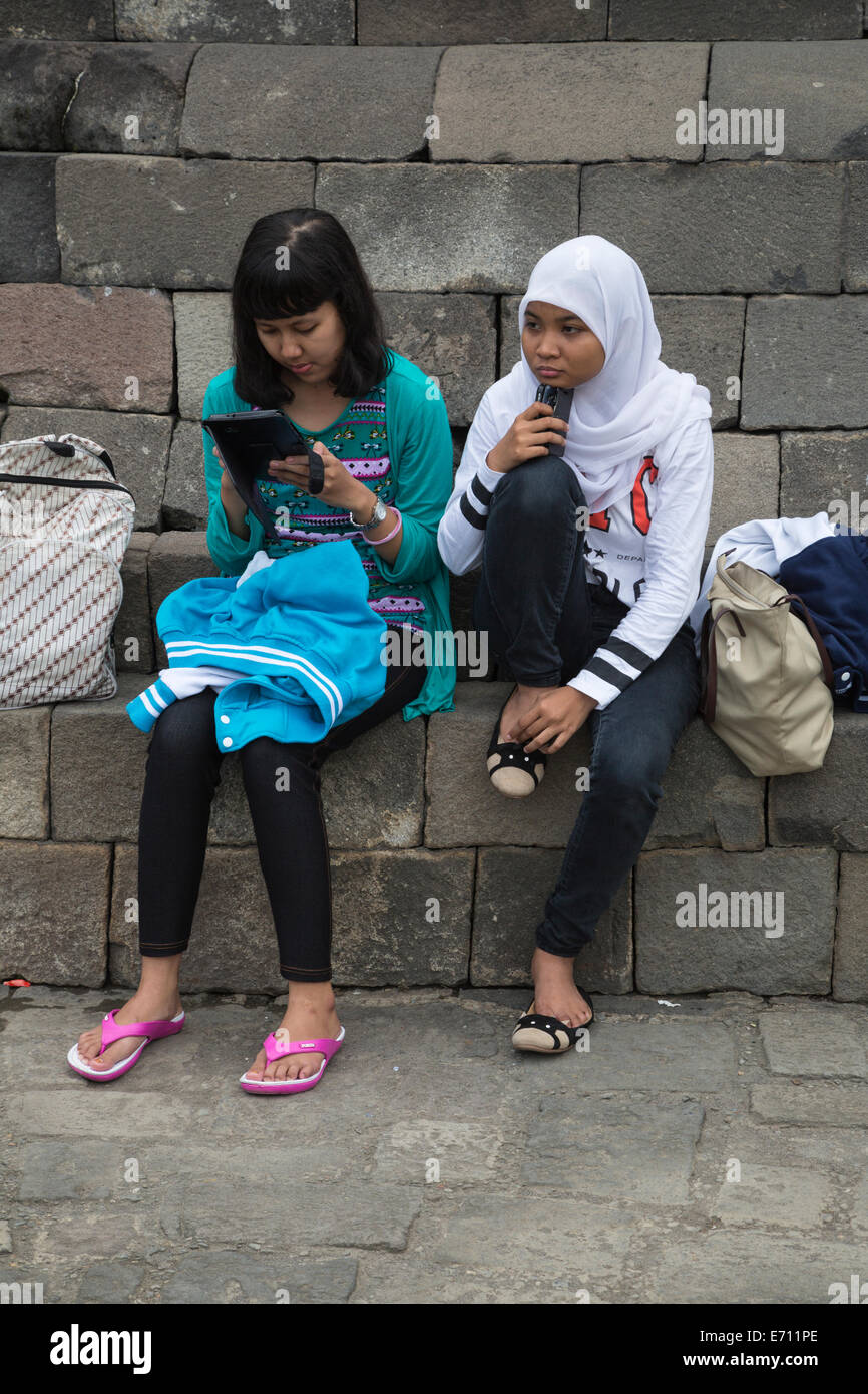 Borobudur, Java, Indonesien.  Zwei junge indonesische Mädchen mit Handy und iPad. Stockfoto