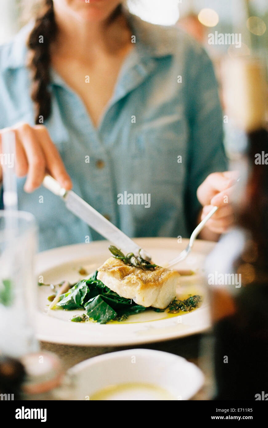 Eine Frau, ein Essen, ein Gericht aus Fisch und grünem Gemüse zu essen. Stockfoto