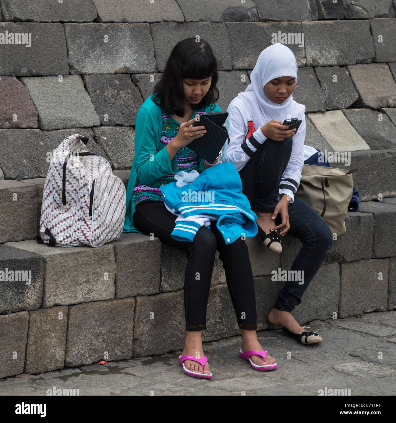 Borobudur, Java, Indonesien.  Zwei junge indonesische Mädchen mit Handy und iPad. Stockfoto