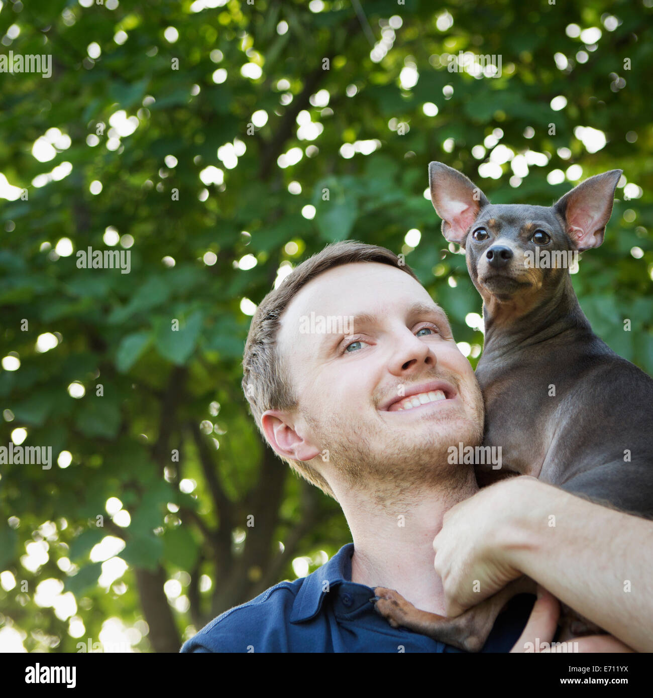 Ein Mann mit einem kleinen Hund auf seinen Schultern. Stockfoto