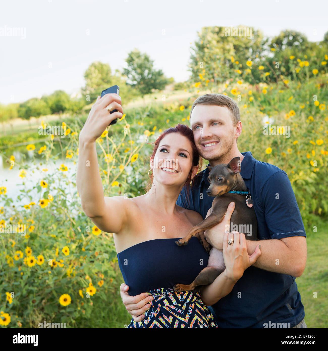 Ein paar spielen mit ihren kleinen Hund in den Park nehmen eine selfy. Stockfoto