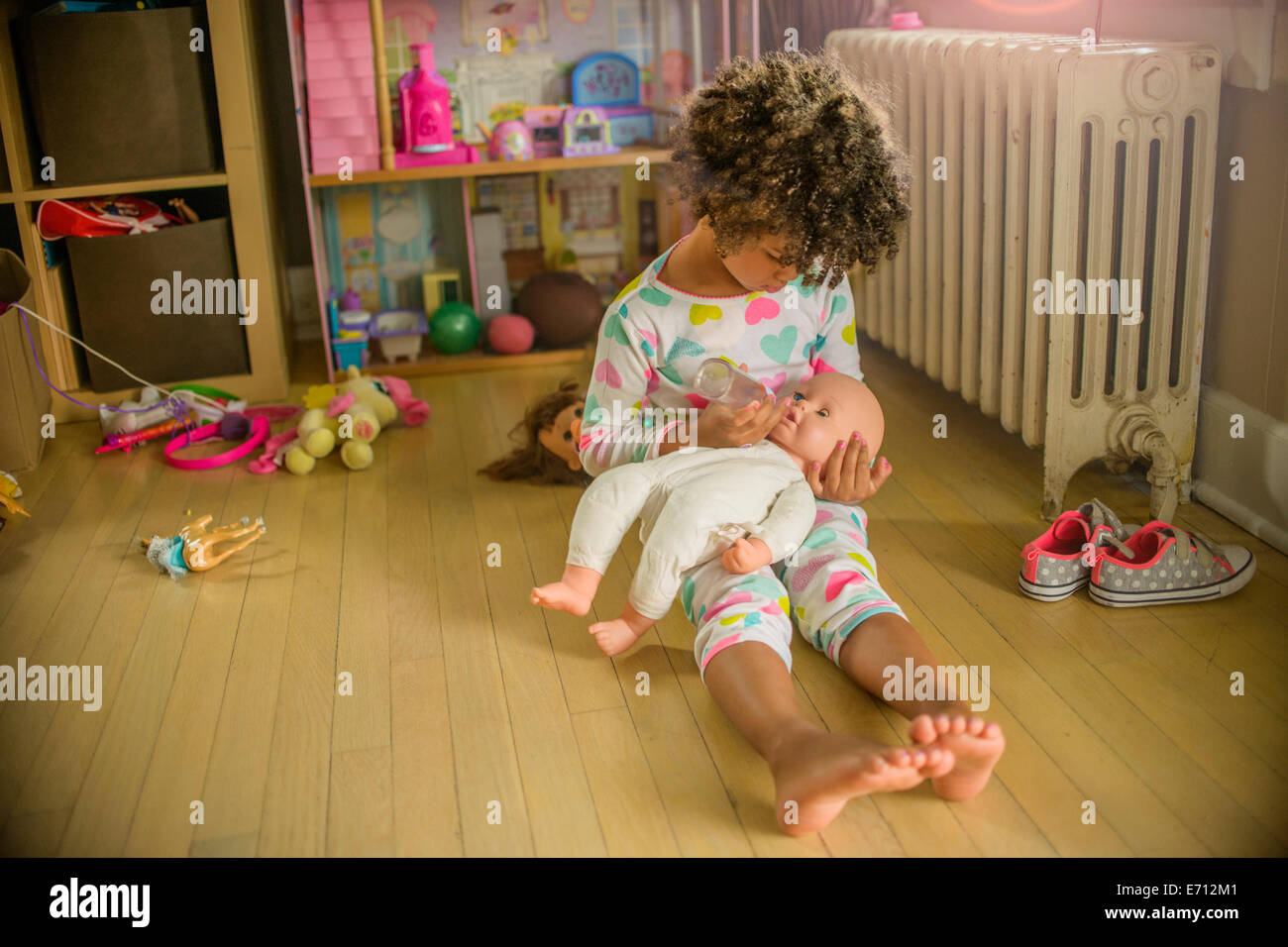 Mädchen sitzen im Spielzimmer Stock Fütterung Puppe Stockfoto