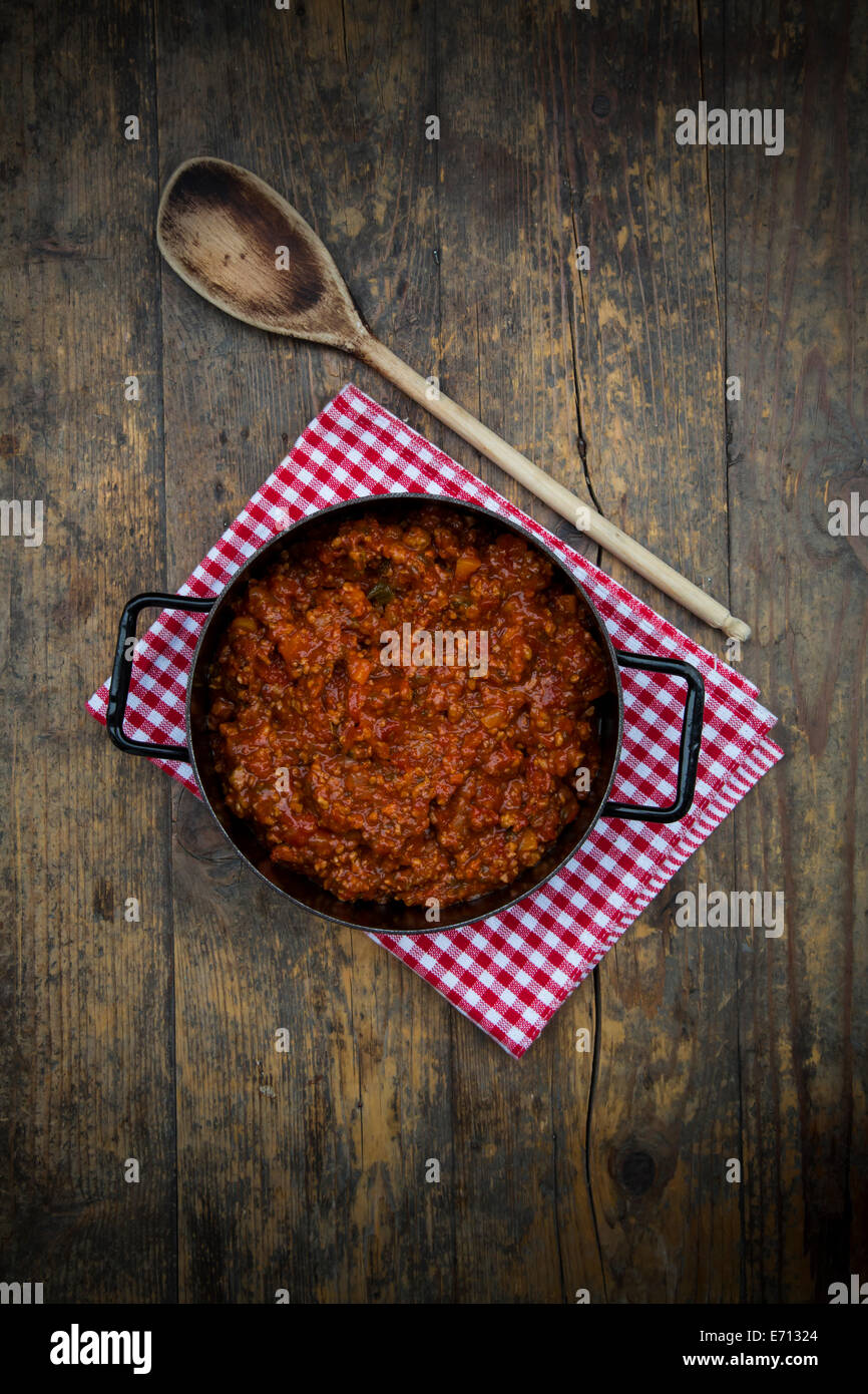 Kochtopf der Bolognese-Sauce, Tuch und Holzlöffel auf dunklem Holz, erhöhten Blick Stockfoto