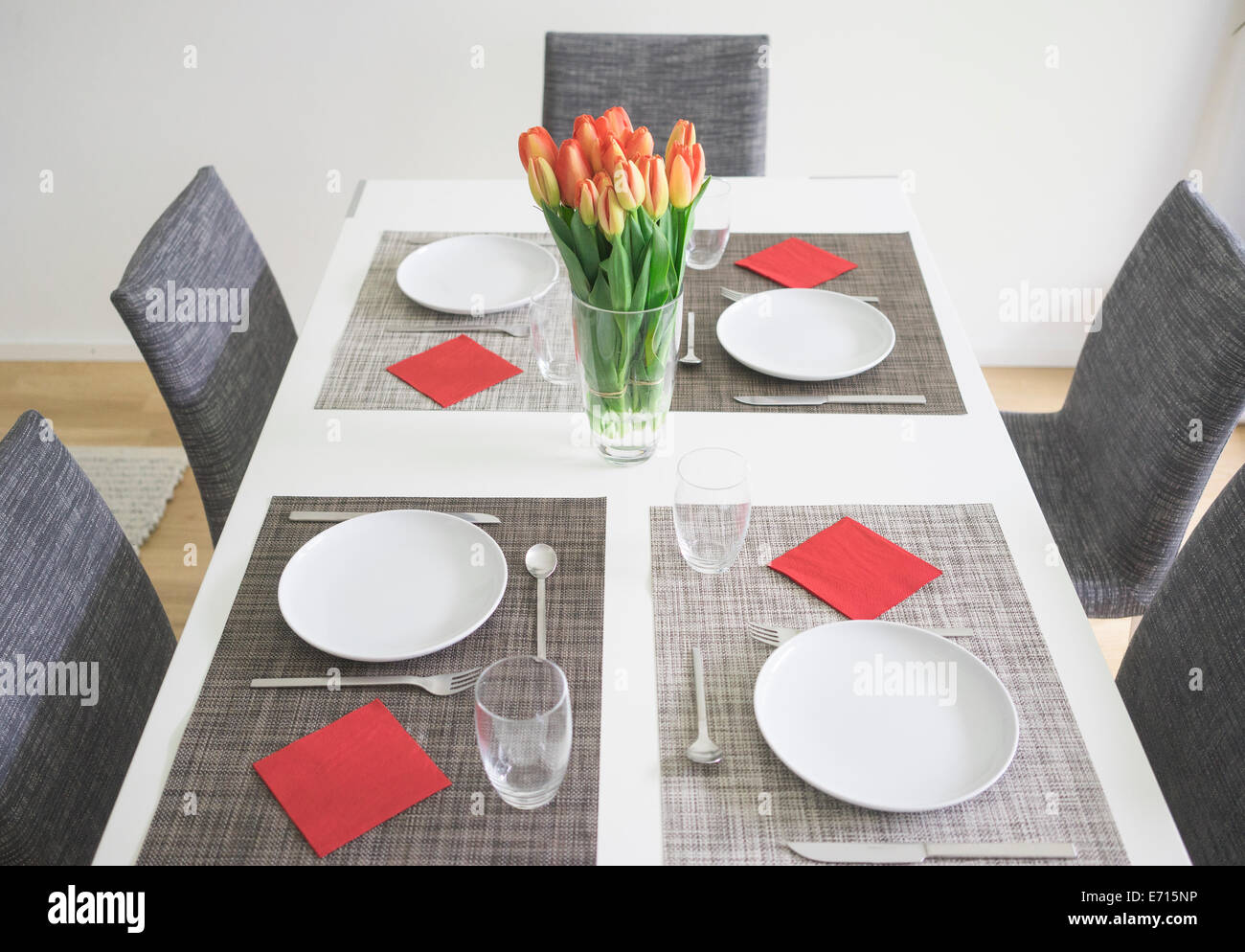 Gedeckten Tisch für vier Personen mit Blumenvase mit Tulpen Stockfoto