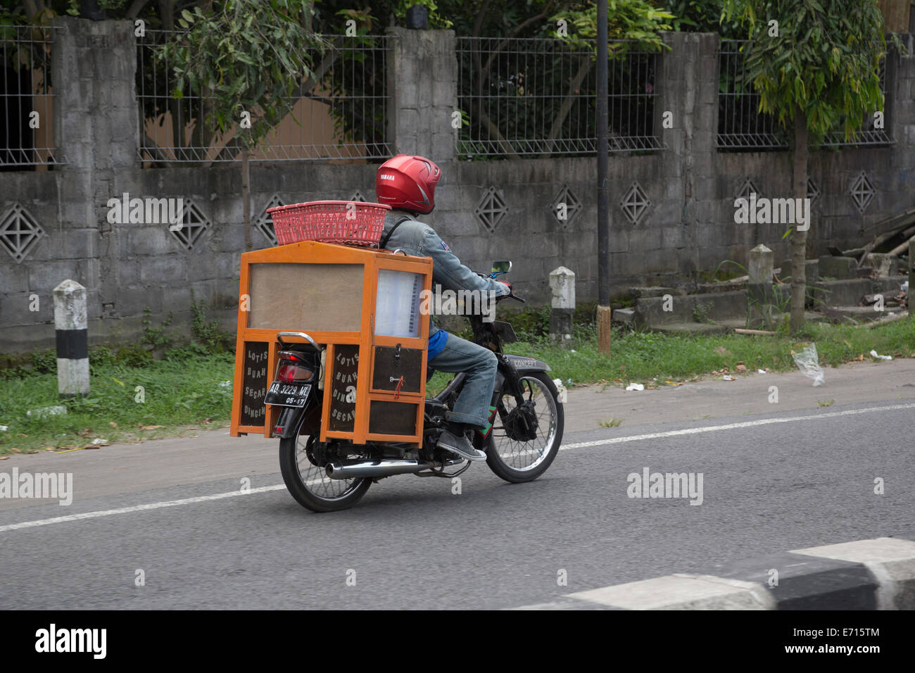 Yogyakarta, Java, Indonesien.  Motorrad mit Verkäufers stehen auf Rücken getragen. Stockfoto