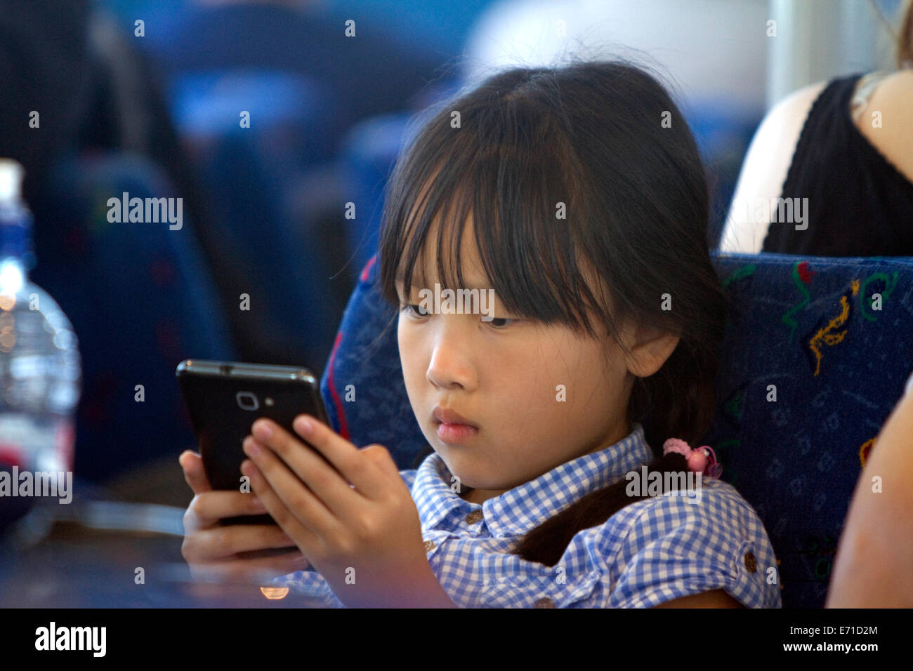 Asiatische Mädchen spielen mit einem Smartphone unterwegs ein Ausflugsschiff in der Bay of Islands, Nordinsel, Neuseeland. Stockfoto