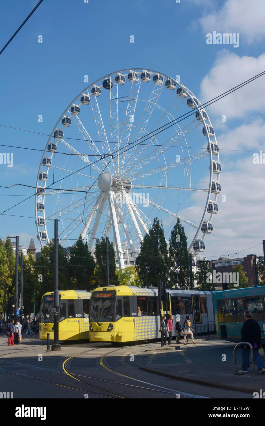 Metrolink Straßenbahnen durch Piccadilly, Manchester, mit dem Manchester-Auge im Hintergrund. Stockfoto