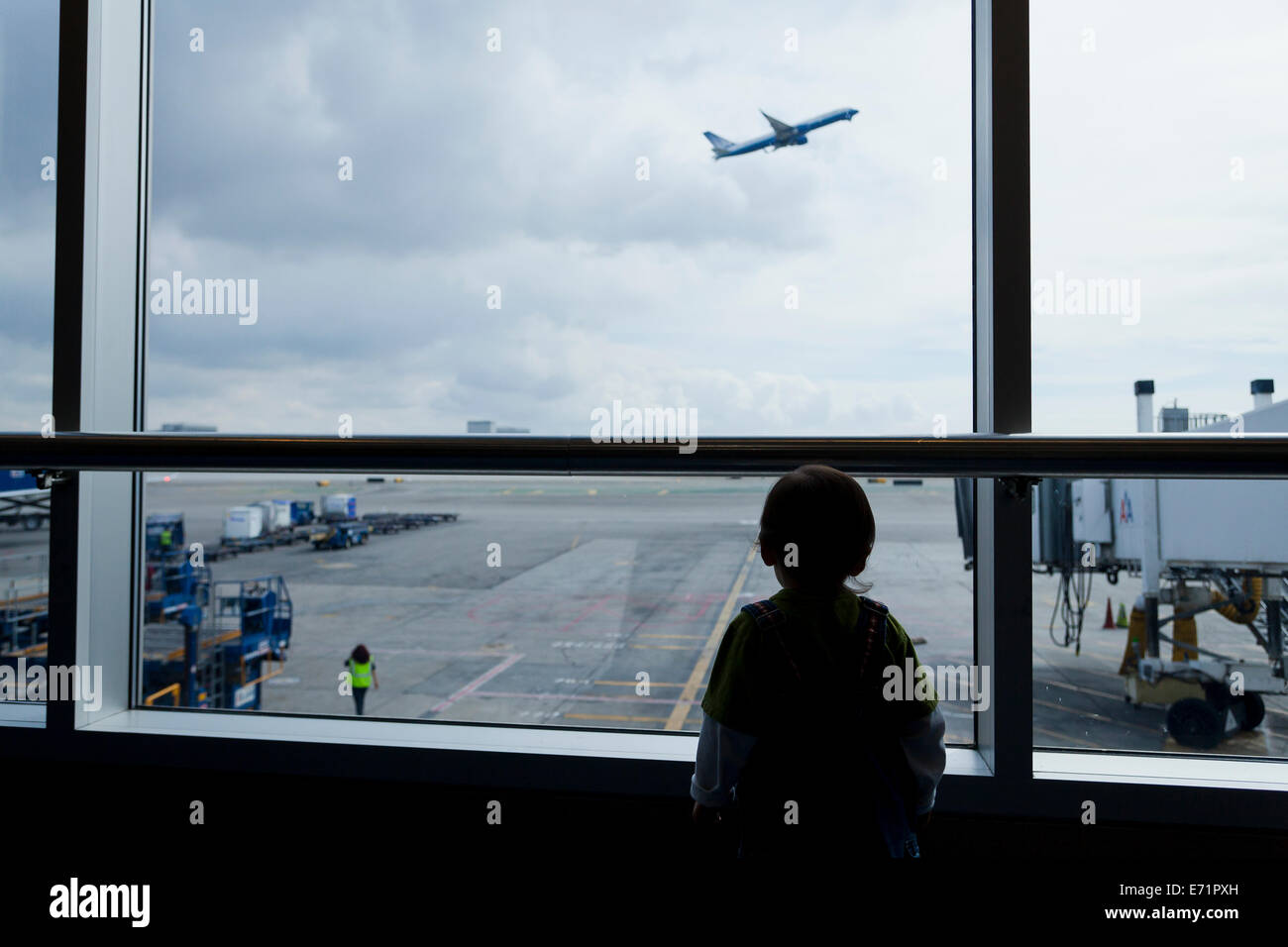 Kleines Kind gerade ausgeschiedenen Verkehrsflugzeug durch Flughafen Fenster - USA Stockfoto