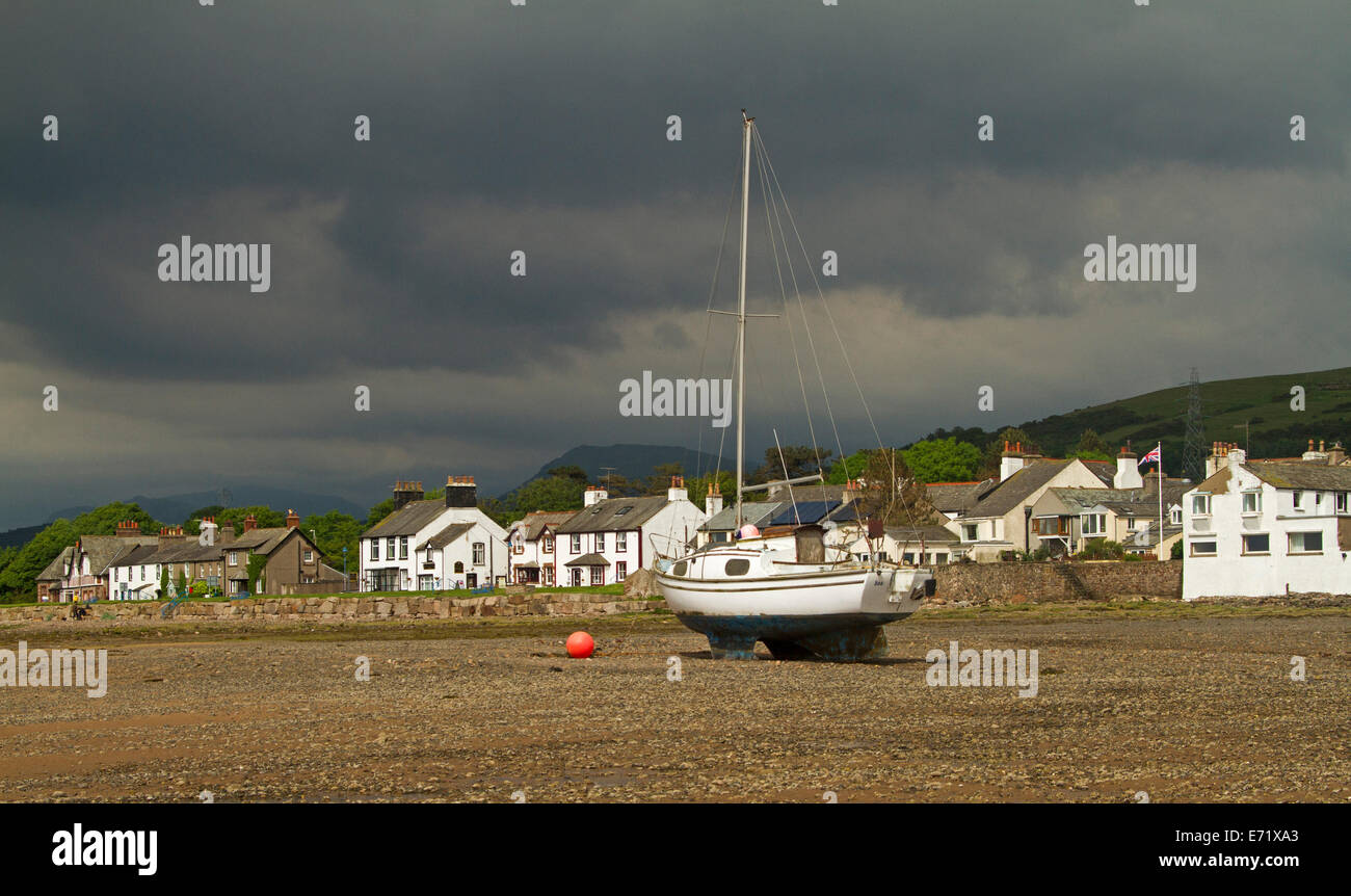 Am Strand Häuser und Boot am Strand bei Ebbe mit stürmischen Himmel im küstennahen Dorf von Ravenglass, Cumbria, England Stockfoto