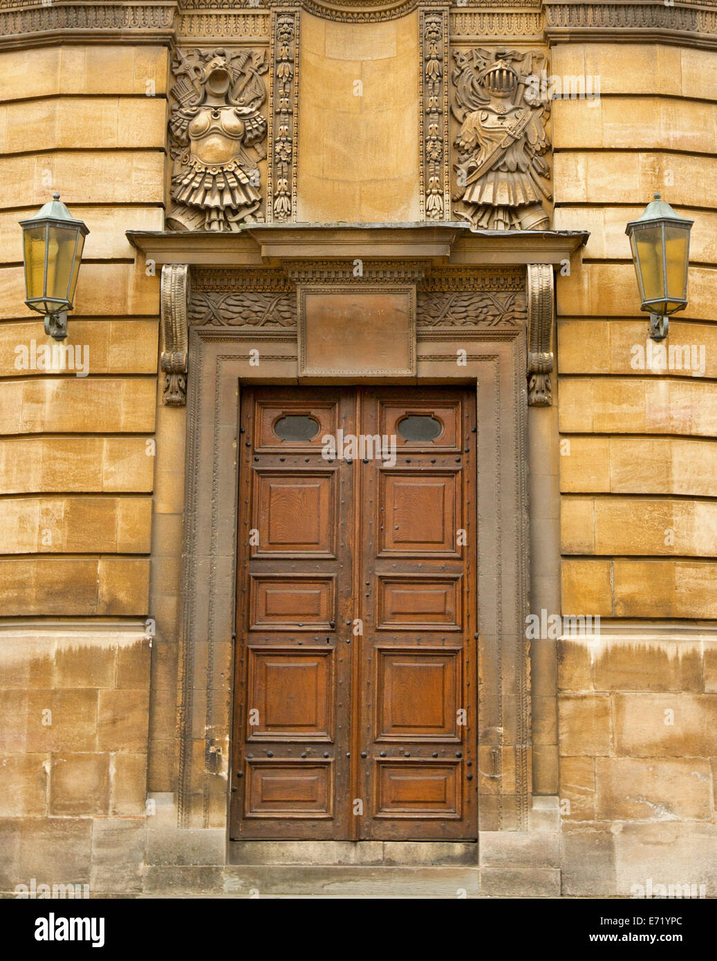 Verzierte braunen hölzernen Doppeltüren mit rechteckigen Platten und sehr dekorativ geschnitzten Stein Rahmen in der Wand des historischen Gebäudes in Oxford, England Stockfoto