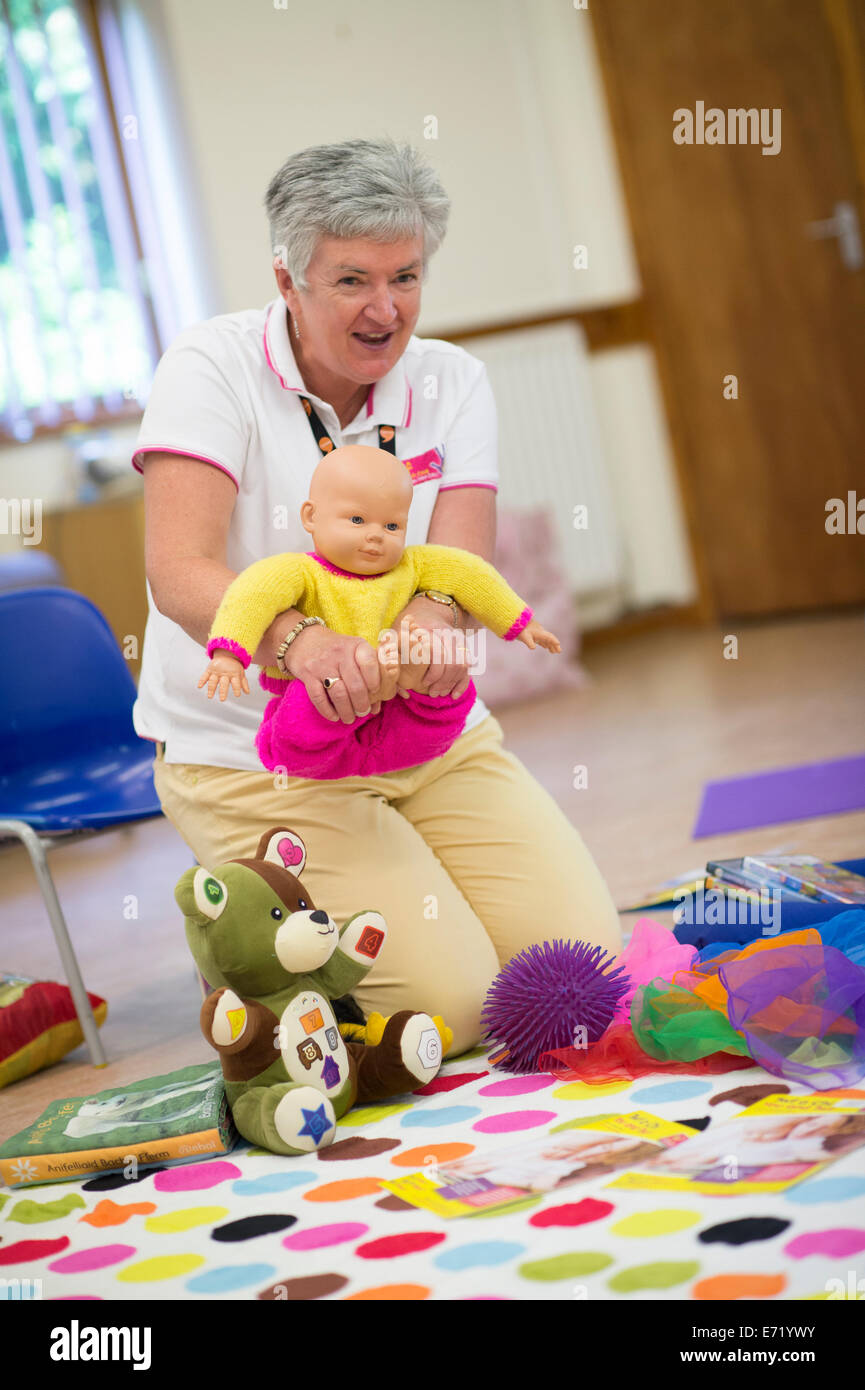 Eine Frau führt eine Vorschule Spielgruppe zeigt, wie man ein Baby für eine Massage, Wales UK halten Stockfoto