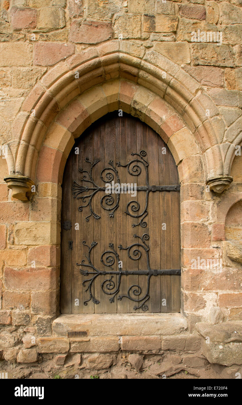 Holztür mit riesigen spektakulären und dekorative Scharniere in verwitterten Steinwand an Ruinen der historischen Bolton Priorat England gewölbt Stockfoto