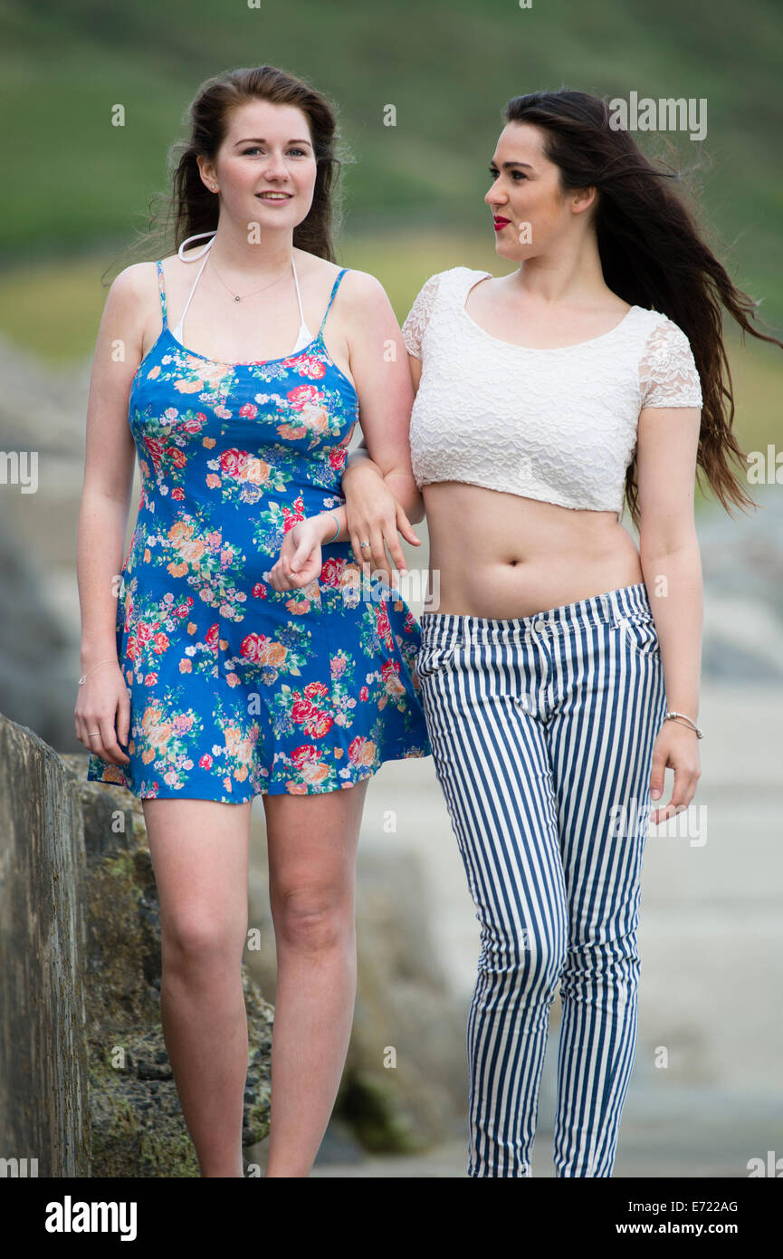 Freundschaft zwischen Frauen: zwei junge glücklich lächelnde Mädchen Freunde späten Teenager Anfang 20 ist in Arm arm im freien UK Stockfoto