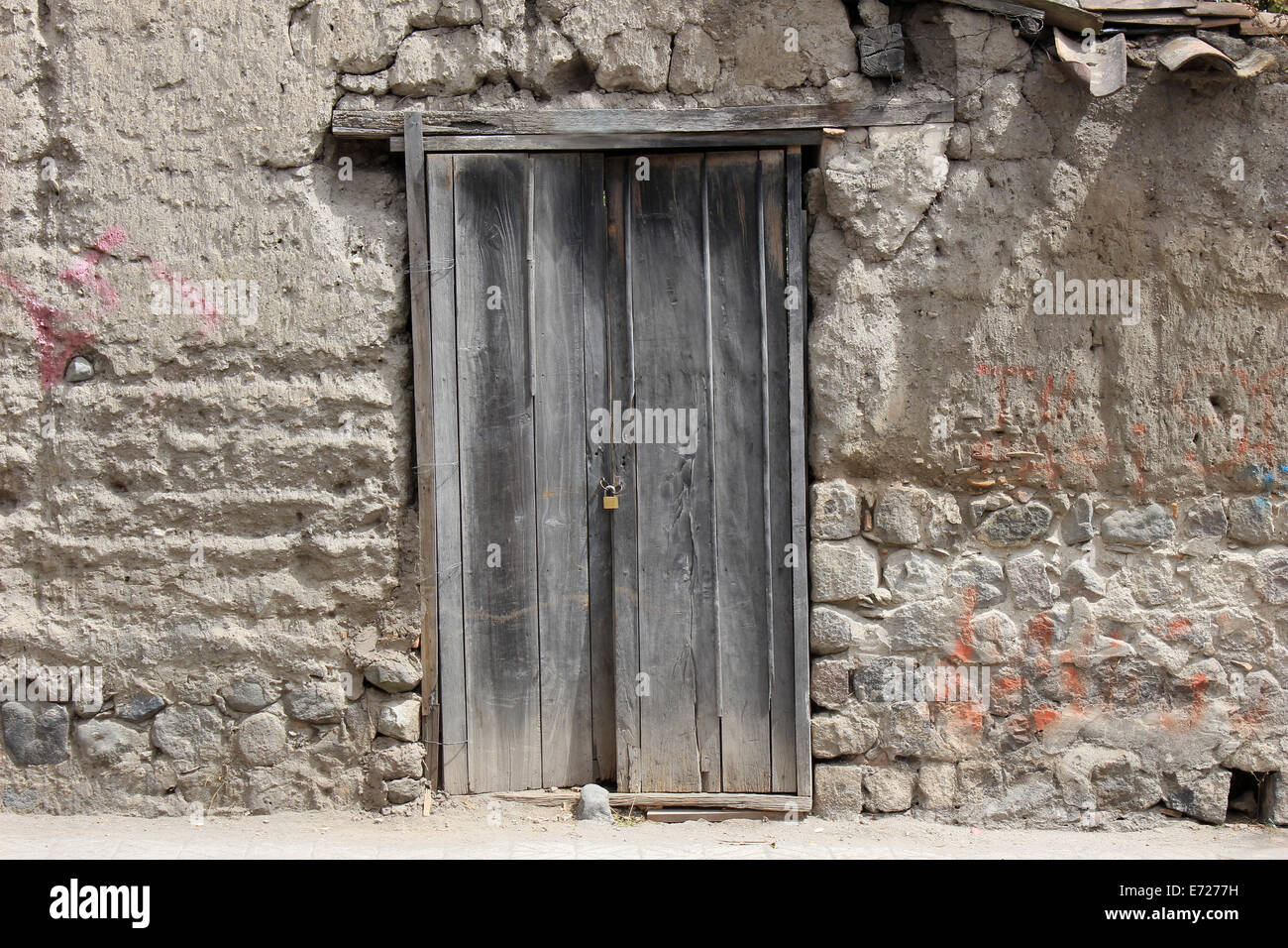 Eine verwitterte Holztür in eine alte Mauer neben einer Eigenschaft in Cotacachi, Ecuador Stockfoto