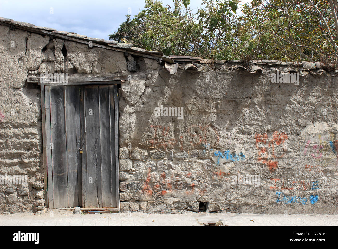 Eine verwitterte Holztür in eine alte Mauer neben einer Eigenschaft in Cotacachi, Ecuador Stockfoto