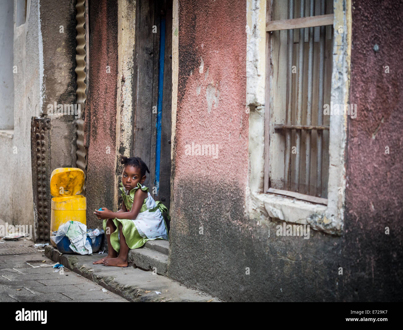 Ein Mädchen sitzt auf einer der Straßen von Stone Town auf Sansibar. Stockfoto