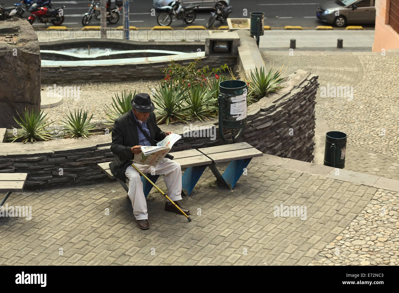 Mann sitzt auf einer Bank und liest eine Zeitung in einer kleinen Passage in Quito, Ecuador Stockfoto