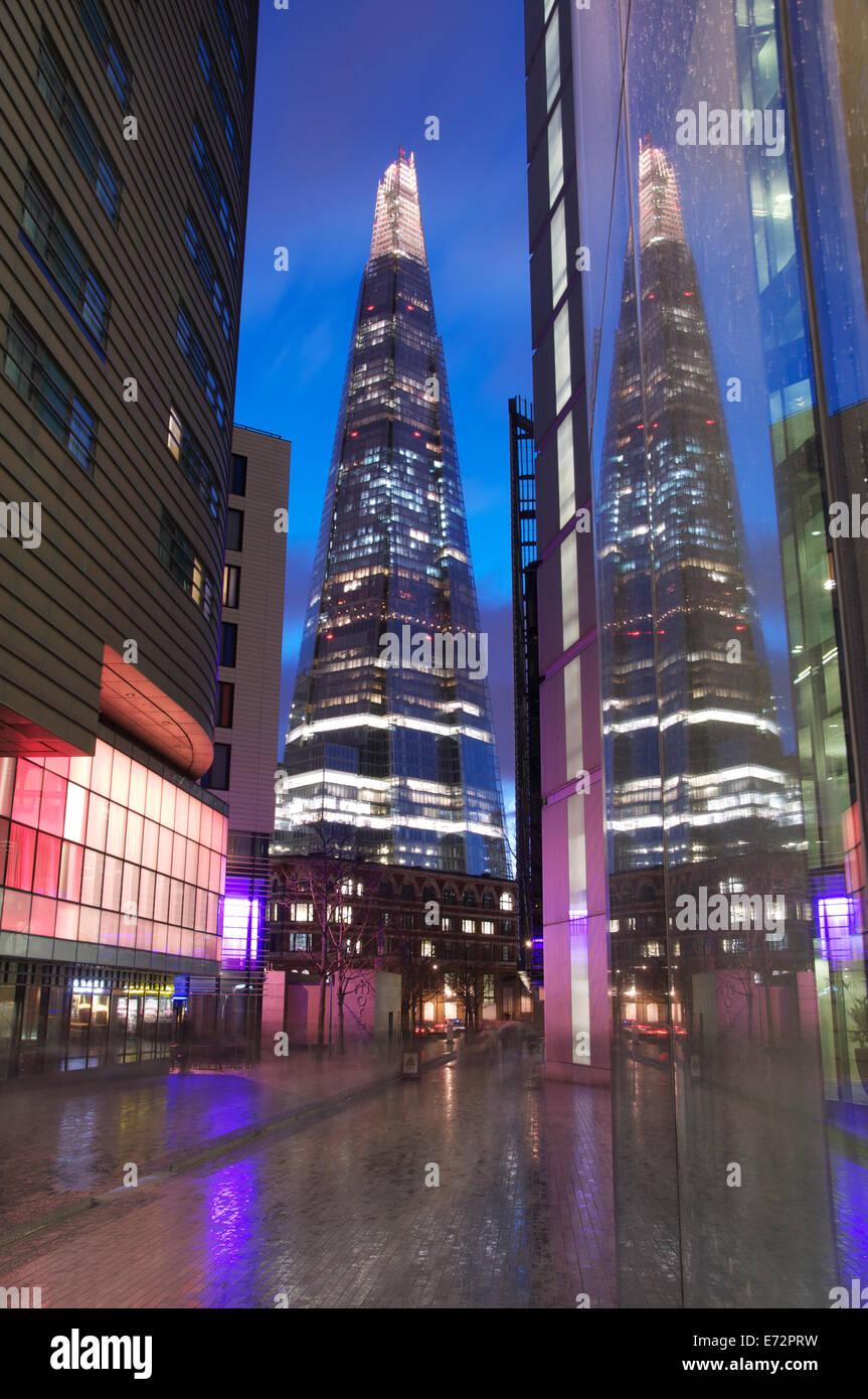 Der Shard in den Fenstern der modernen Bürogebäuden von mehr London Ort widerspiegelt. Neon Lichter leuchten auf dem nassen Fahrbahnen. London, England, UK. Stockfoto